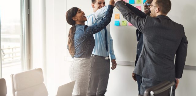 Successful diverse multiracial business team giving a high fives gesture as they celebrate in a conference room in an office